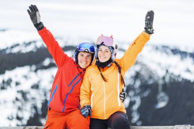 Kayak arkadaşları ahşap çitte eğleniyor. Açık havada poz vermeyi seven bir çift. Kayakçı çocuk ve kız.