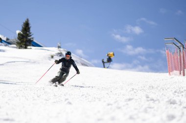 Profesyonel kayakçı bir dağ kışlığında yamaçlarda kayak yapıyor. Açık gökyüzü ile güneşli bir gün.