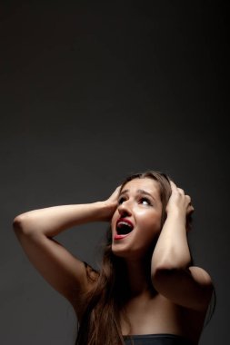 Güzel bir stüdyo resmi. Karanlık arka planda el ve yüz hareketleri yapmak.