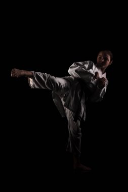 Karate yapan genç bir kız. Siyah arkaplana karşı kimonolu çocuk.