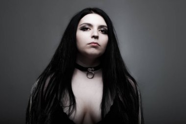 Koyu gri arka planda beyaz gözlü, uzun siyah saçlı gotik kız..