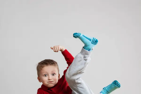 若い男の子が足で背中にバランスを取り 空中に手を挙げている おかしなハッピーフェイス表現 カメラを見る ロイヤリティフリーのストック画像