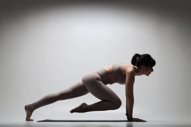 Yoga pozu veren beyaz güzel bir kadın. Esneme egzersizleri yapan bir kızın yarı silüeti..