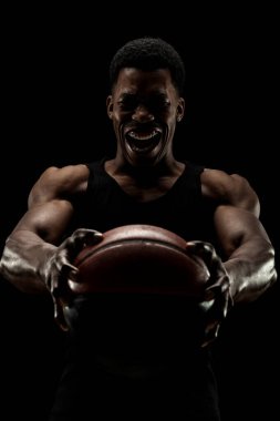 Basketbolcu siyah arka planda topu tutuyor. Çığlık atan Afro-Amerikan erkek silueti.