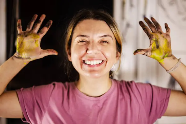 Happy Female Artist Displays Her Colorful Paint Stained Hands Broad lizenzfreie Stockbilder