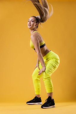 Sarı kıyafetli güzel kız dans eden zumba. Koyu sarı ya da turuncu arka plana karşı mutlu dans hocası.