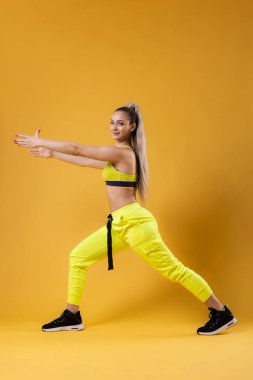 Sarı kıyafetli güzel kız dans eden zumba. Koyu sarı ya da turuncu arka plana karşı mutlu dans hocası.