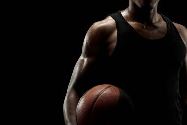 Basketbolcu siyah arka planda topu tutuyor. Yoğunlaşmış ciddi bir Afro-Amerikan erkeği. Kaslı kişi kenar silueti.