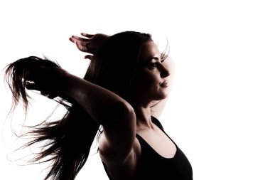 Uzun siyah saçlı genç bir kadının silueti. Beyaz arka planda dikilip etrafa saç saçıyor..