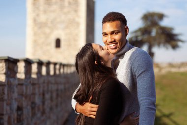 Multiracial couple posing on the walls of an old fortress. Man and woman in love.