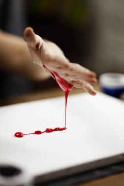 Kadın sanatçı elinde kırmızı renkle sanatsal bir tablo yapıyor.. 