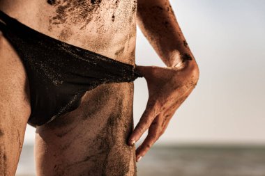 Genç bir kadının yakın çekimi, kumlu ve güneşli, okyanus arkaplanı olan bir plajda duruyor, boş zamanları ve yazın neşesini simgeliyor..