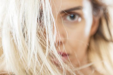 Bu görüntüde genç bir kadın var. Sarışın, rüzgârlı saçları yüzünü kısmen gizliyor. Gizemli ve dramatik bir görünüm sergiliyor..