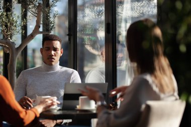 Three friends in a restaurant talking smiling and drinking tea. Business colleagues having a meeting after work or during coffee break at a cafe bar.