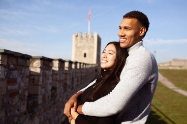Multiracial couple posing on the walls of an old fortress. Man and woman in love.