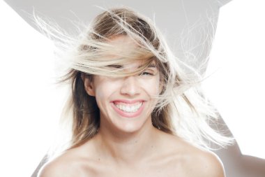 Gülümseyen, saçları uçuşan, beyaz bir şemsiye altında beyaz bir stüdyonun arka planında poz veren neşeli bir genç kadın..