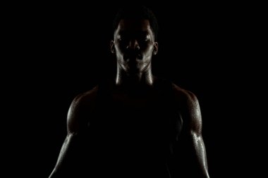 Yoğunlaşmış ciddi bir Afro-Amerikan erkeği. Terli, kaslı, kenar ve siluet..