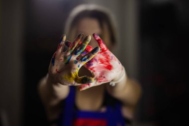 Bir kadın sanatçı, sanatsal çevresindeki yaratıcılığı ve tutkuyu sembolize ederek, rengarenk boyalı ellerini gösteriyor..