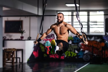 Odaklanmış bir atlet, canlı, kentsel bir çalışma alanında halkalar üzerinde zorlu bir jimnastik egzersizi gerçekleştirir..