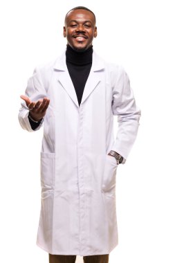 Beyaz önlüklü doktor gülümsüyor ve tıbbi ortamda profesyonelliği ve arkadaşlığı sembolize eden hoş bir jest sunuyor..