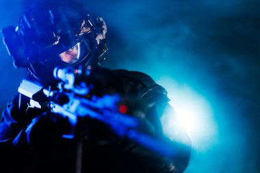 A professional tactical operator is prepared for action, showcasing advanced equipment in a dramatic illuminated environment, highlighting readiness, technology, and precision. clipart