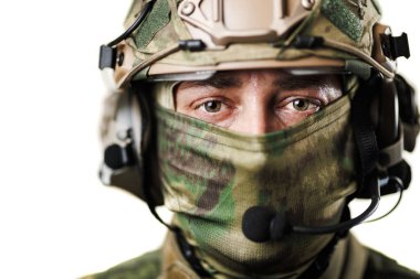 Miğferli ve kamuflaj maskeli bir askerin detaylı görüntüsü, gözlerini ön plana çıkarıyor..