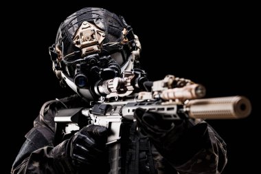 Ağır donanımlı bir asker, yüksek teknolojili optiklere sahip bir tüfeği hedef alıyor, taktik bir kask ve teçhizat takıyor, karanlık bir geçmişe karşı hazırlık ve savaş odağı sergiliyor..
