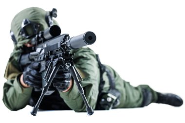 Silahlı bir asker, silahlı ve silahsız bir şekilde, taktiksel bir çatışmada, ileri teçhizat ve stratejik savaş görevlerine odaklanmış vaziyette yatıyor..