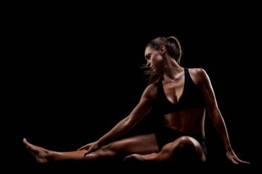 Atletik kıyafetli bir insan karanlık bir arka planda geriliyor. Zindelik, sağIık ve adanmışlığı temsil eden poziyonları zarafet ve güç yayar. Yoga, farkındalık ve egzersiz gibi kavramlar için uygundur..