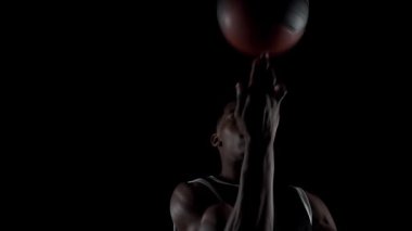 Basketbolcu topu çeviriyor. Siyah arka plan üzerinde çalışan Afrikalı Amerikalı sporcu.