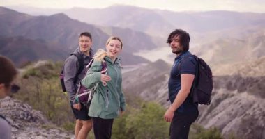 Sırt çantalı bir grup arkadaş dağlarda yürüyüş yapıyor. Sarılmak ve manzaranın tadını çıkarmak için mola veriyorlar. Doğada neşe ve beraberliği ifade ediyorlar..