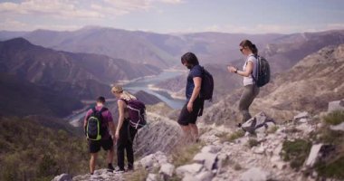 Bir grup arkadaş sakin göle bakan dağlık bir alanda yürüyüş yapıyorlar. Manzaradan hoşlanırlar, sohbet ederler ve doğanın huzurunu birlikte yaşarlar..