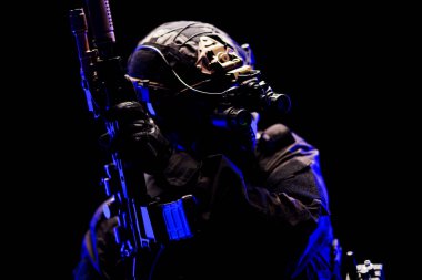 Siyah üniformalı, gece görüş gözlüklü, düşük ışık koşullarında silah kullanan bir taktik asker. Savaş, teknoloji ve dövüş temalarını çarpıcı bir ortamda gözler önüne seriyor..