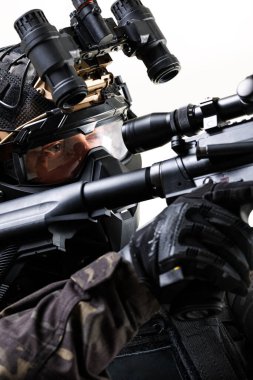 Tüfek, gece görüş gözlüğü ve koruyucu miğfer de dahil olmak üzere ileri taktik teçhizatlı bir askerin yakın çekimi, düşük ışıktaki özel görevlerde hazırlık ve hassasiyeti gösteriyor.