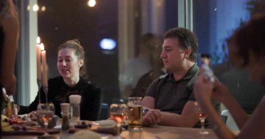 Arkadaşlar birlikte bir restoranda akşam yemeği yiyip mum ışığında sohbet ediyorlar..