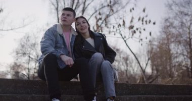 Genç aşık çift parkta birlikte vakit geçirir, merdivenlerde oturur ve geleceği hayal eder..