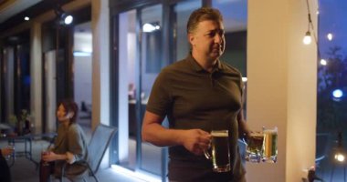 Arkadaşlar sıradan bir arka bahçe partisinde içki içip sohbet etmekten zevk alıyorlar. Sıcak atmosfer sicim ışıklarıyla güçlenir ve rahatlatıcı bir ortam yaratır..