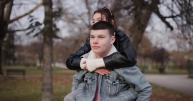 Genç bir adam kız arkadaşını parkta sırtında taşır. Telefonuyla selfie çekiyor. İkisi de mutlu ve eğleniyorlar..