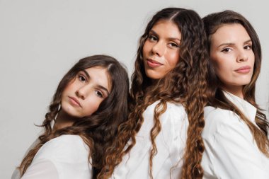 Beyaz giyinmiş, özgüven, dostluk ve dayanışmayı ifade eden üç kadının yakın çekimi. Olumlu duygular, bağlılık duygusu ve karşılıklı destek..