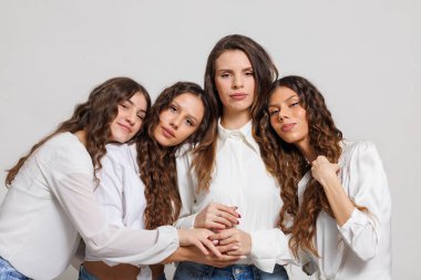 Birbirine yakın dört kadından oluşan bir grup, sade bir stüdyo arka planında dostluğu, birlikteliği ve modern tarzı sembolize eden, günlük moda ve doğal ifadeleri sergiliyorlar..