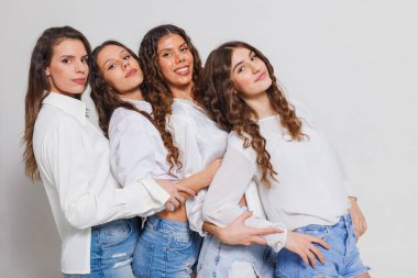 Beyaz gömlekler ve kot giyip, birlikte poz veren ve arkadaşlık, zarafet ve bireysellik duygusu taşıyan bir grup genç kadın. modern gençlik bağlantıları.