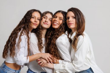 Stüdyo ortamında yakalanan dört kadın, günlük zarafetle gülümseyip kucaklaşıyorlar. Olumlu ifadeleri mutluluk, birlik ve dostluk yayar..