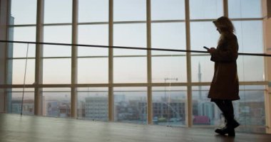 Priştine ve Kosova 'ya bakan geniş pencereli çağdaş bir binada genç bir kadın yürüyor ve konuşuyor.