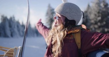 Genç bayan kayakçı Kopaonik dağındaki bir asansörden manzaranın keyfini çıkarıyor. Gülümsüyor ve yamacın zirvesine çıkarken manzaranın tadını çıkarıyor..