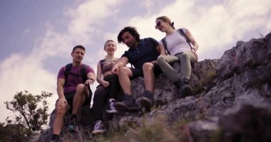 Yürüyüşte eğlenen dört arkadaştan oluşan bir grup beşlik çakarken ve kayalık bir dağın tepesinde selfie çekerken yakalandı. Neşeli ruhları ve yoldaşlıkları parlıyor.