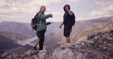 Üç arkadaş dağlarda yürüyüş yaparken muzaffer bir anın tadını çıkarıyor. Çak bir beşlik ve nefes kesen doğal manzaranın arka planına karşı neşeli anı yakalıyorlar..