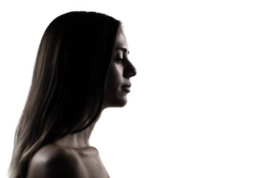 Bu resim, yüksek kontrastlı ışıklandırmalı genç bir kadını, stüdyo ortamında temiz çizgilerle huzurlu bir profil sunarken yakalıyor..