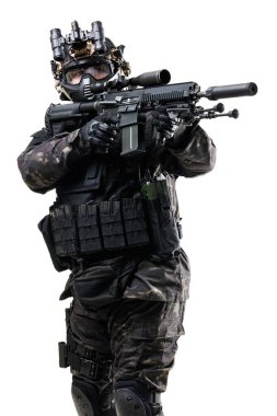 Taktik kamuflaj teçhizatı giymiş ağır donanımlı bir asker, bir askeri veya terörle mücadele senaryosunda profesyonellik, gizlilik ve eyleme hazır olma tasvir eden bir silah taşıyor..