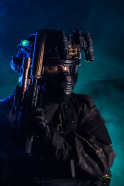 Siyah üniformalı, gece görüş gözlükleri ve tüfekle atmosferik dumanın ortasında taktik operatör, dramatik, yüksek riskli bir ortamda gizlilik, strateji ve modern savaş temalarını çağrıştırıyor..