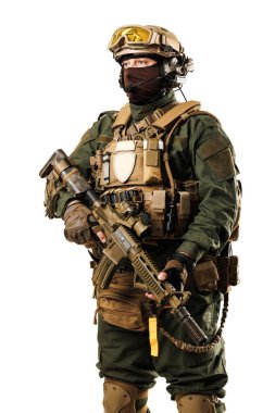 Taktik teçhizat giymiş bir asker, miğfer, kamuflaj giysileri ve tüfek dahil, güvenle operasyona hazır bekliyor.